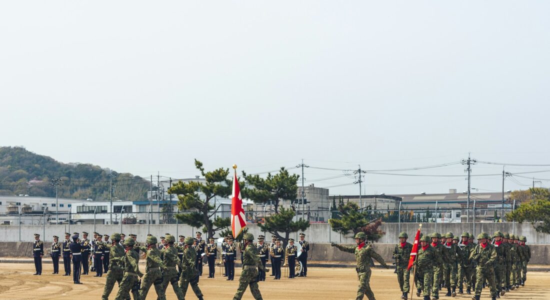 Soldiers in formation marching with flags on parade ground
