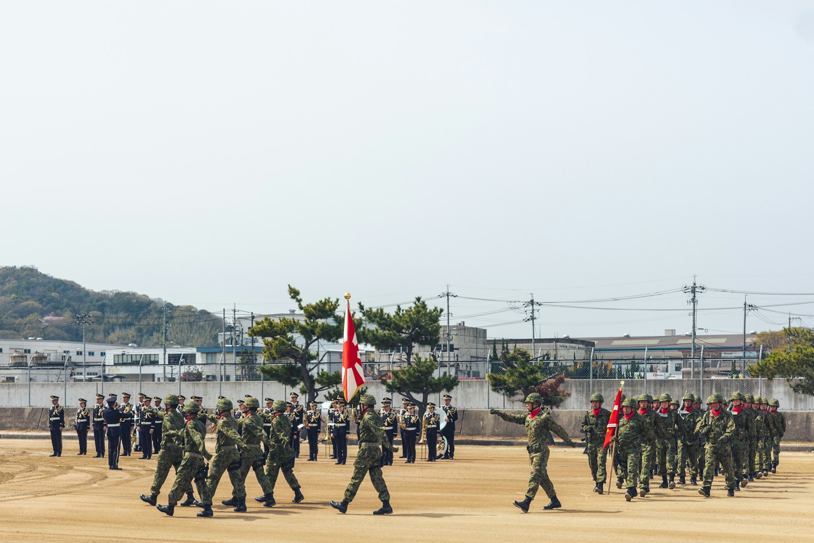 Soldiers in formation marching with flags on parade ground