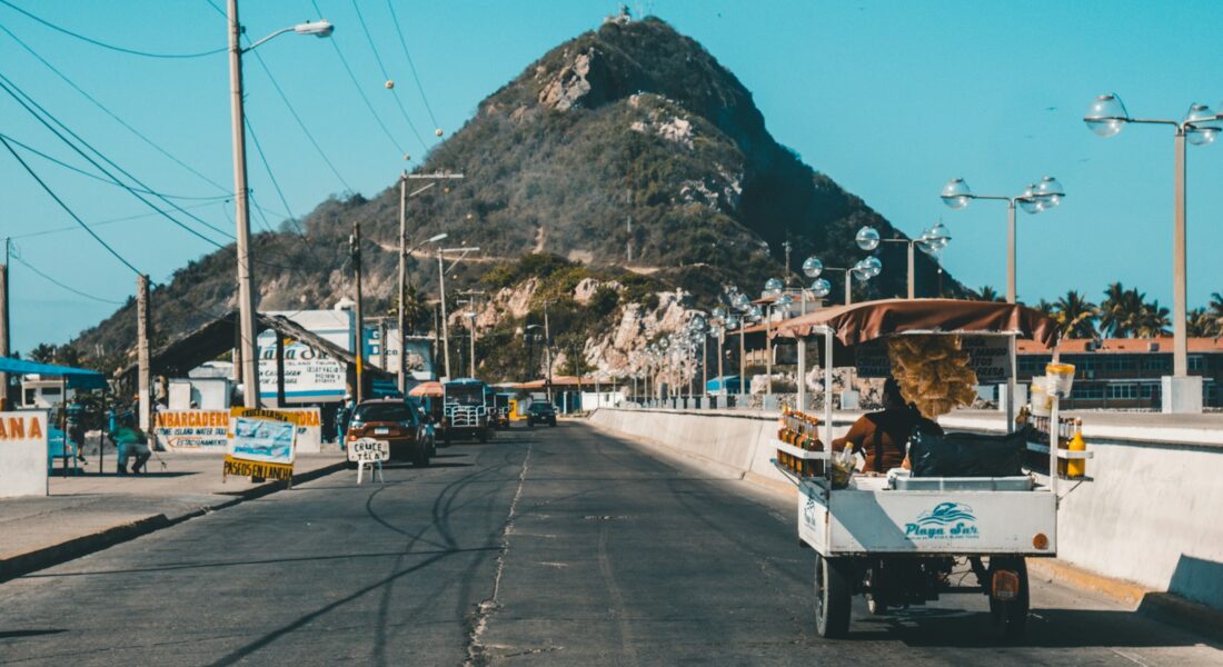 white auto rickshaw on riding on asphalt road towards green mountain