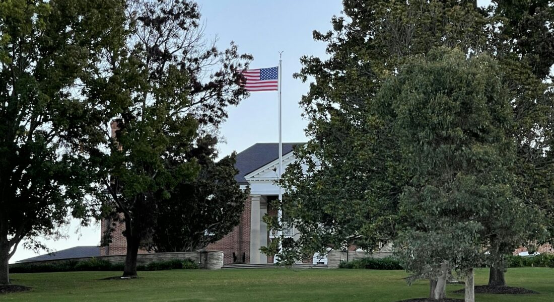 green grass field with green trees and us a flag on top during daytime