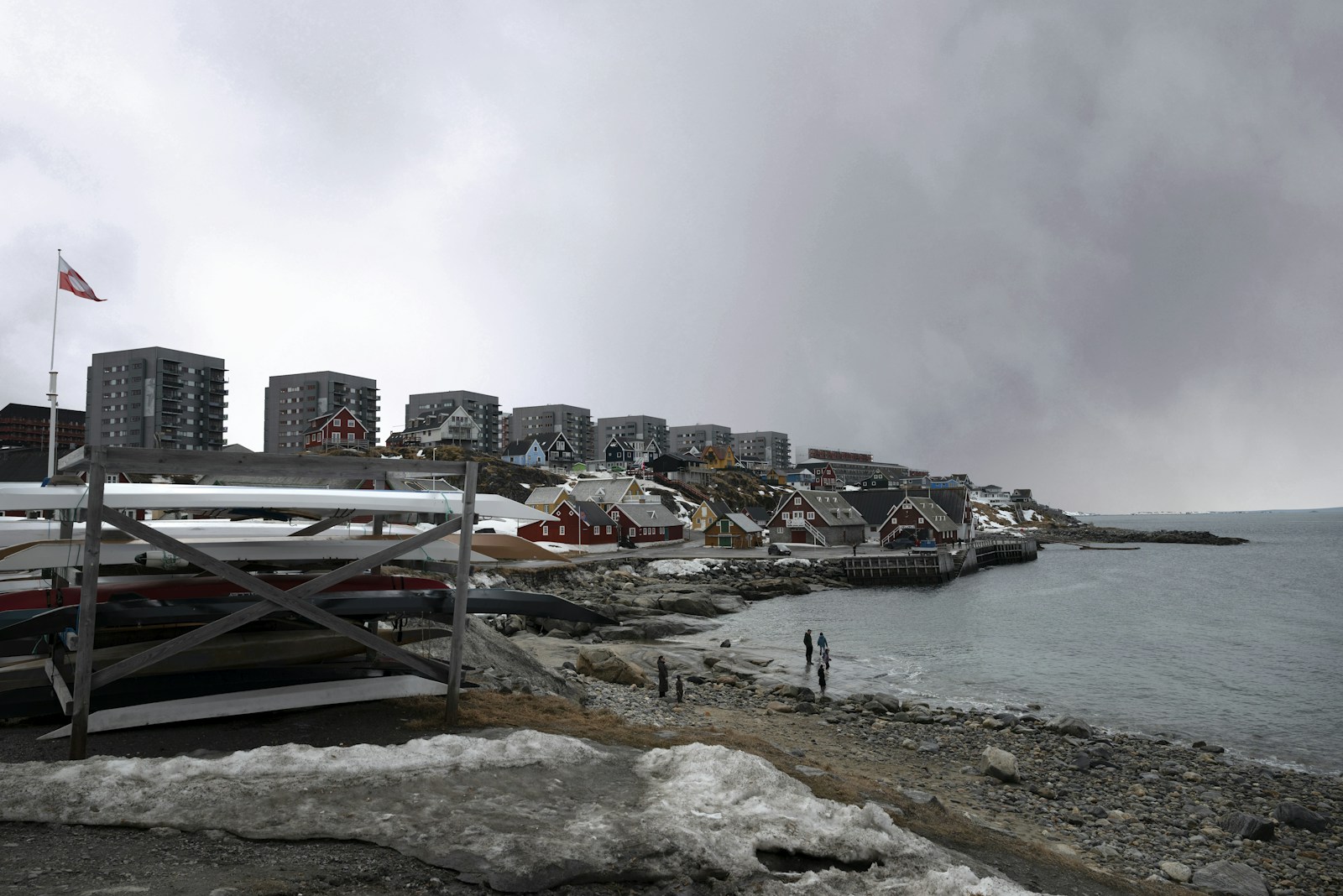 Northern coastal town with buildings, boats, and snow.